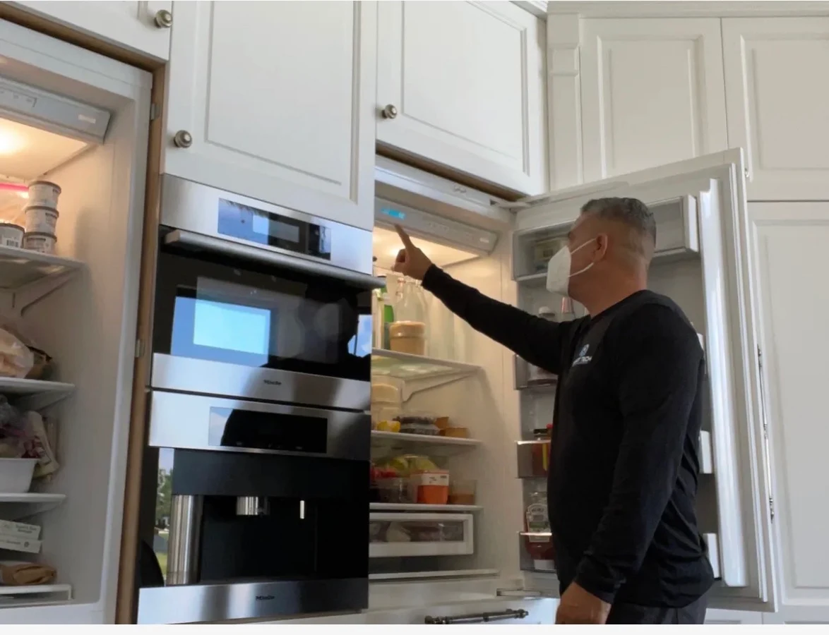 Technician adjusting the controls inside a built-in refrigerator